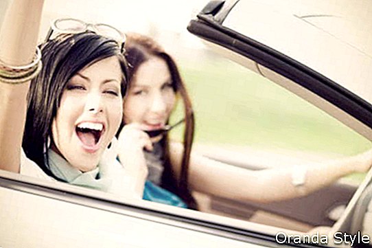 Kaksi iloista ystävää valkoisessa autossa, joka ajaa kaikkialle ja etsii vapautta ja hauskaa