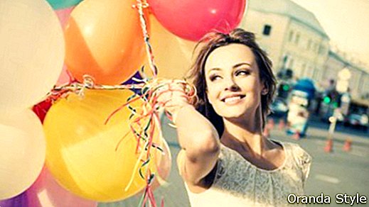 Õnnelik noor naine värviliste lateksballoonidega