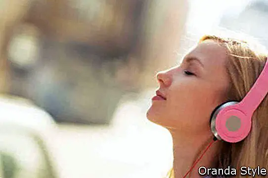 Wanita muda mendengar muzik di fon kepala di bandar