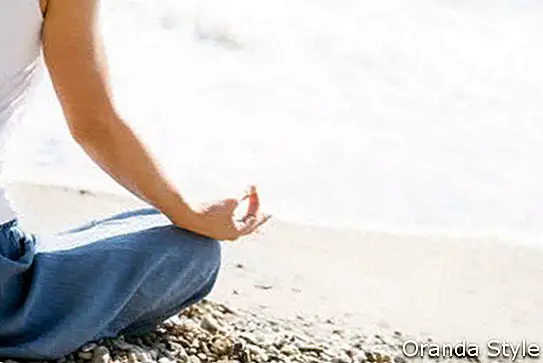 Frau, die am Strand meditiert