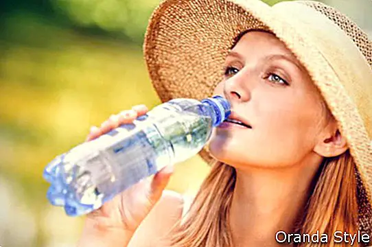 mujer con sombrero agua potable