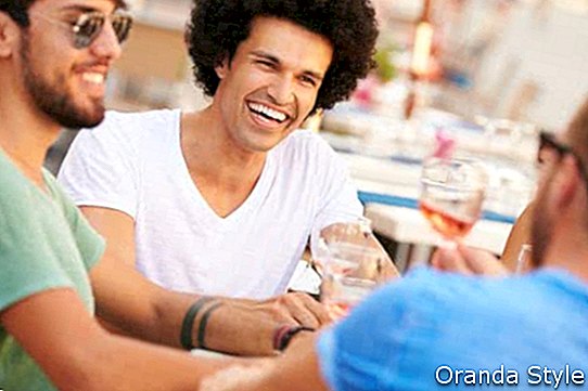 קבוצה של חברים גברים נהנים מארוחה במסעדה בחוץ