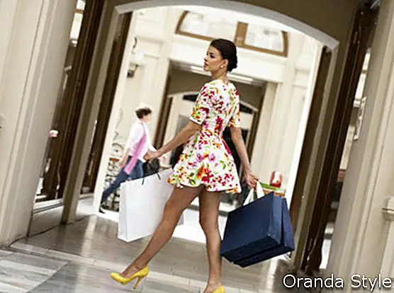 Красива млада жена в цветя с бяла рокля, ходеща в магазина