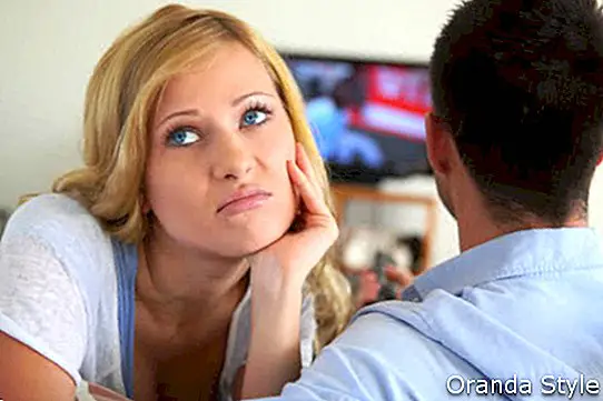 Mujer rubia aburrida viendo televisión con novio