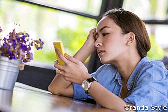 Красива млада азиатска жена е самотна В очакване на телефона в кафене