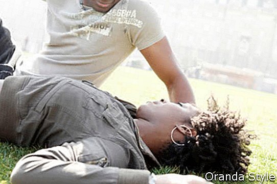 Joven pareja afroamericana hablando mientras se relajan acostado sobre la hierba verde en la ciudad de Londres.