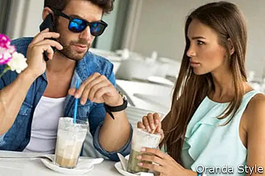ชายหนุ่มรูปหล่อกับหญิงสาวสวยในร้านกาแฟคุยกันทางโทรศัพท์