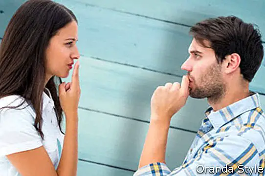 Razburjen mlad par se ne pogovarja proti pobarvanim modrim lesenim deskam