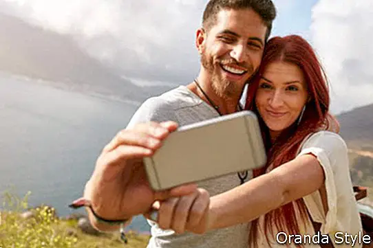 Junge Paare, die selfie mit intelligentem Telefon nehmend wandern