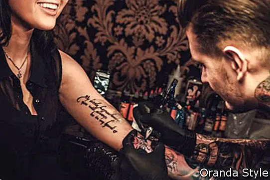 Professionell tatuerare gör en tatuering på en ung flickahand