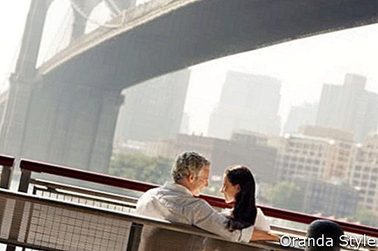 Hintere Ansicht eines Paares, das auf Bank unter Brooklyn-Brücke sich entspannt