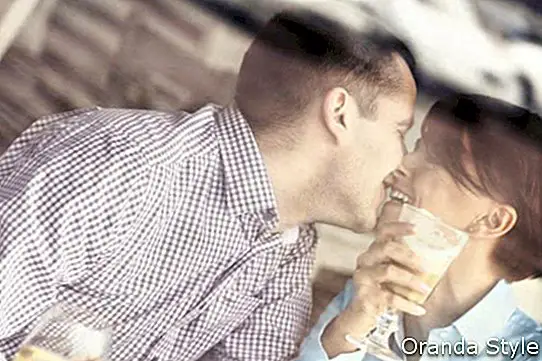 ungt par kysser på en restaurant tatt gjennom et vindu