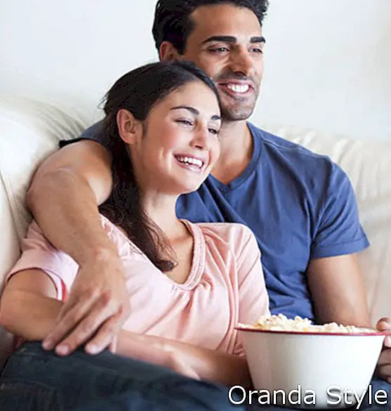 млада двойка гледа филм и яде пуканки