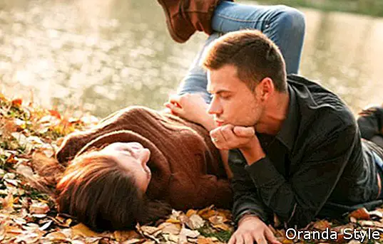 mladý muž a žena ležiace pri jazere hovoriť