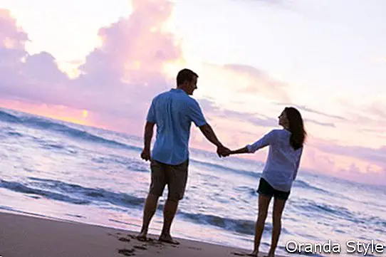 Unga älskare som går på stranden vid solnedgången på tropisk semester