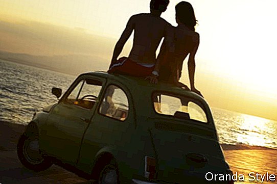 pasangan pada waktu matahari terbenam di pantai dengan kereta