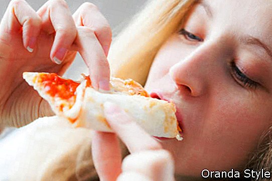 אישה שמחה צעירה אוכלת פיצה