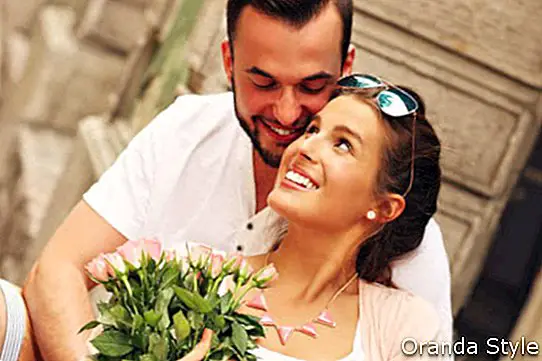 Una foto de una joven pareja romántica con flores en la ciudad