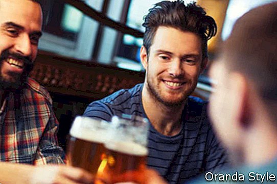 glückliche männliche Freunde, die Bier trinken und Gläser an der Bar oder an der Kneipe klirren