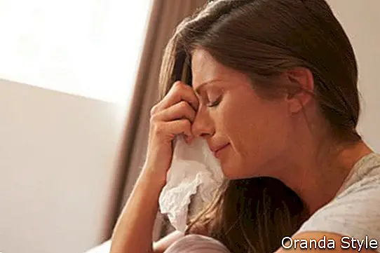 Žena trpí depresiou, sedí na posteli a plače