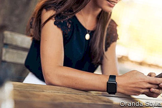 Skrivande textmeddelande för kvinna på den smarta telefonen i ett kafé