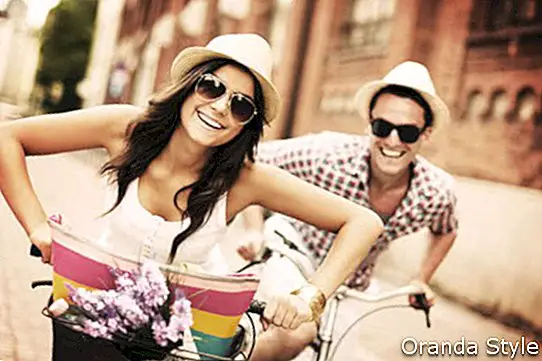 Laimīgs pāris brauc ar velosipēdu pa pilsētu