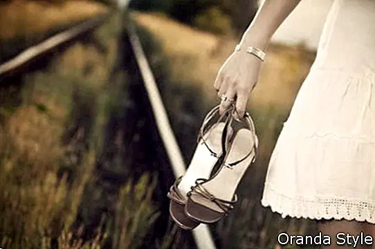 Hand der jungen Frau mit Schuhen auf der Eisenbahn