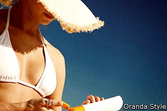 moteris su apsauginiu kremu nuo saulės paplūdimyje