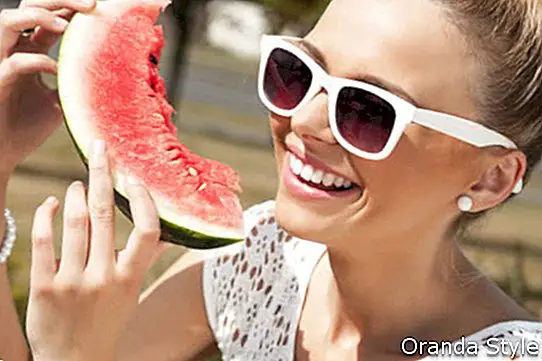 Ung smilende kvinne tar vannmelon