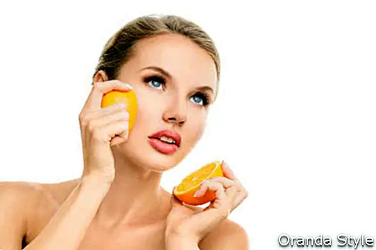 Joven rubia con naranja en sus manos