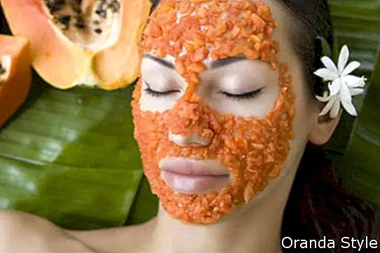 Taikoma graži kaukazietiška moteris, turinti šviežią papajų natūralią veido kaukę
