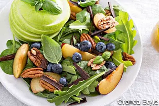 Sveža zdrava solata z listnimi zelenjavami slivovi oreščki in jabolko