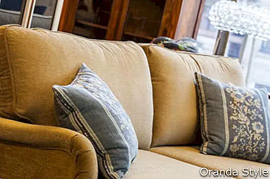 En lysebrun sofa med blå og fløde puder