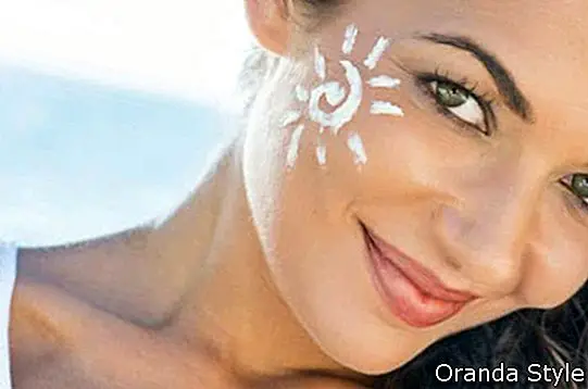 Sorglose junge Frau mit Sonnencreme auf Gesicht am Strand