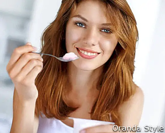 атрактивна млада жена једе јогурт