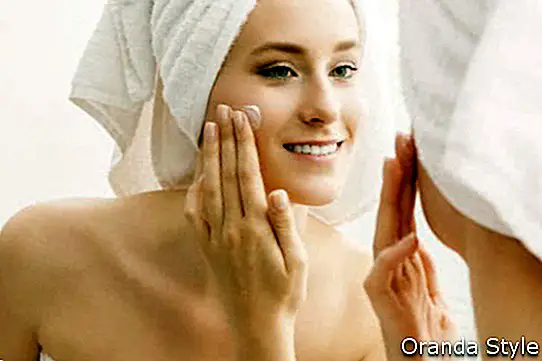 Auftragen von Creme auf ihrem Gesicht nach einer Dusche im Badezimmer