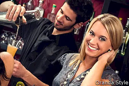 Barmen içki karıştırma sırasında kokteyl barda genç mutlu kız