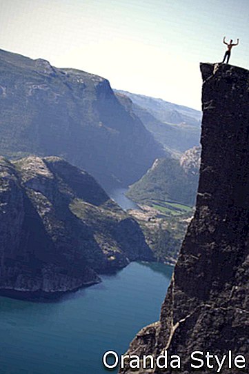vīrietis virs klints Norvēģijas fjordā