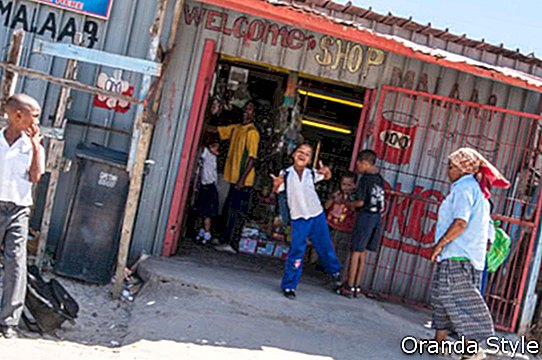 Kinder spielen und posieren für die Kamera vor einem Geschäft in einer südafrikanischen Gemeinde
