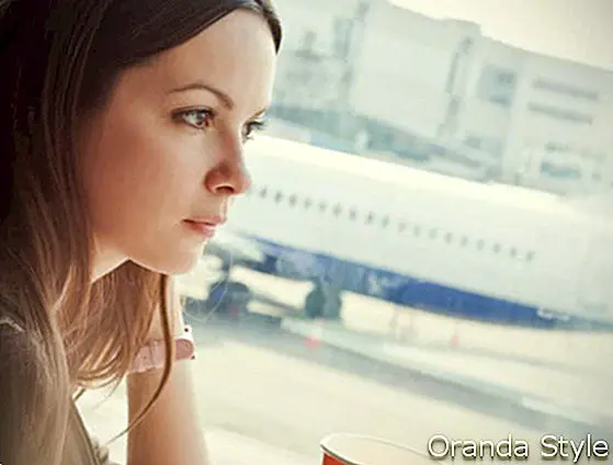 젊은 여자는 공항에서 커피를 마시고있다