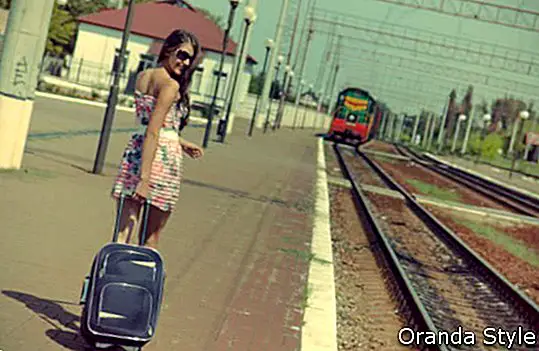 seorang gadis muda yang cantik pergi ke platform stesen kereta api